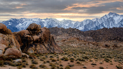 Sunset moment on the mountains with snow and rocks on the foreground