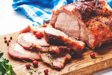 Baked festive pork sirloin with spices and cranberries for sauce, served and sliced on wooden...