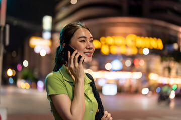 Asian attractive woman backpacker talking on phone while walk in city. 