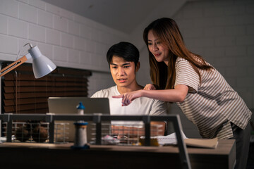 Asian young man overworking at home at night in bedroom with his wife. 