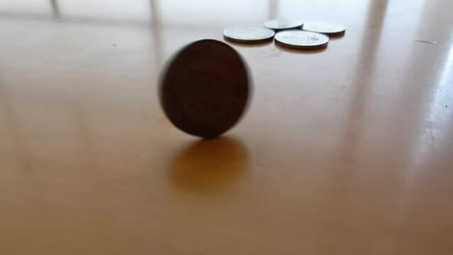 a close-up of a spinning coin on a wooden table - money, economy, risk and gambling concept