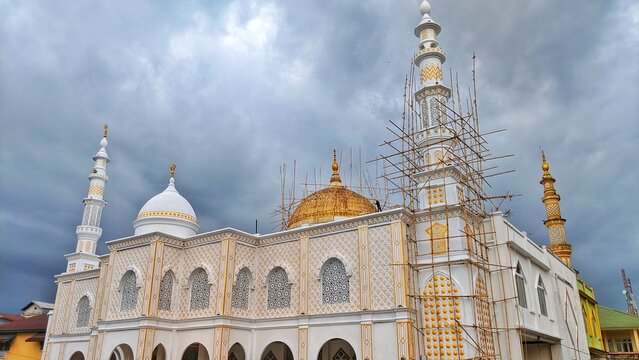 repairing a large mosque using a long bamboo ladder