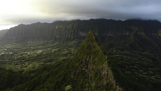 Drone shot in front of a sharp, green mountain peak, unique Hawaiian landscape