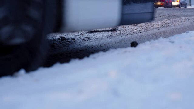 Cars driving though slush snow during snowfall - Close up