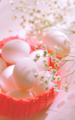 Spring Easter still life. Chicken white eggs in crochet basket with spring flowers on white background
