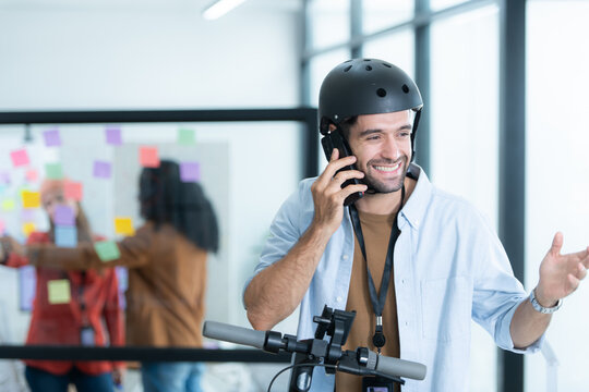Portrait of smiling businessman talking on mobile phone while colleague using scooter in office