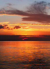 Naklejka premium Sunset sky with reflections in water, sunlight and colored orange clouds