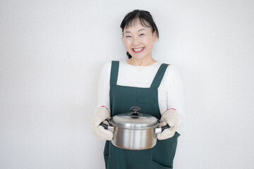 笑顔で鍋を持つ中高年女性