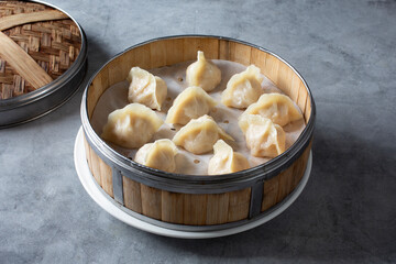 A view of several steamed dumplings inside a bamboo steamer basket.