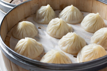 A closeup view of several xiaolongbao dumplings in a bamboo steamer basket.