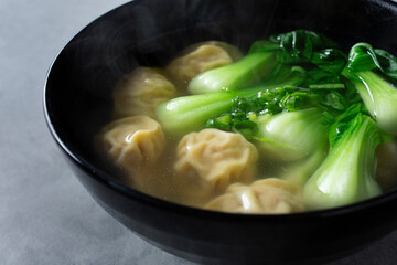 A closeup view of a bowl of wonton soup.