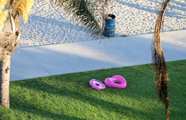 Two inflatable floating devices on the grass near the sand on the bay.