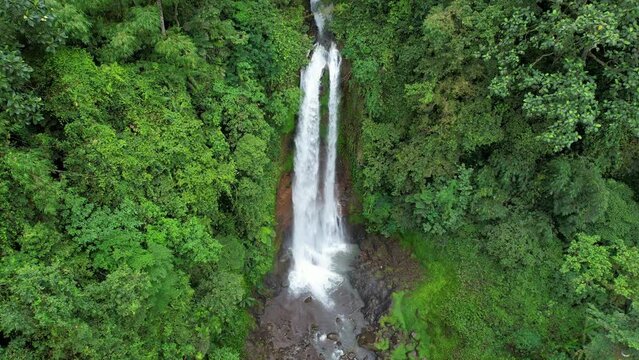 Landing tilt up aerial footage of Gitgit waterfall on cloudy day. Bali, Indonesia.