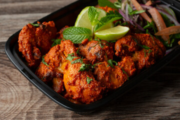 A closeup view of a black container of chicken tikka.