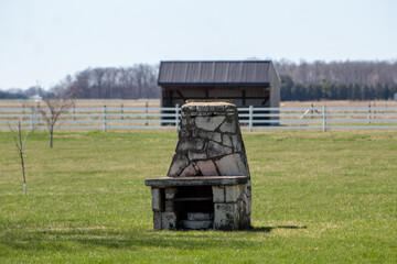 An outdoor stone oven on an open field in the countryside. 