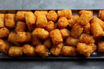 A top down view of a tray full of deep fried tater tots.