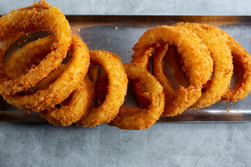 A top down view of a metal tray of onion rings.