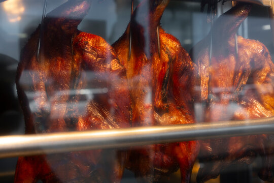 A view of a window display of Peking duck hanging in the front of a local Chinese restaurant.