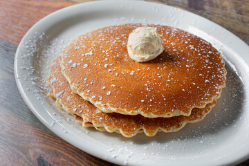 A view of a stack of pancakes, with a dollop of butter spread.