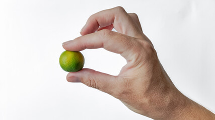 Hand holding a ripe lime with ample copyspace on a white background, ideal for text overlay and...