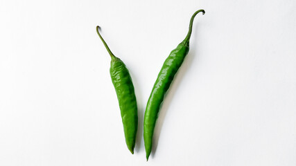 Two fresh green chili peppers isolated on a white background with ample space for text, ideal for culinary themes and spicy food concepts