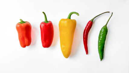 Colorful bell and chili peppers aligned on a white background with copy space, ideal for culinary themes and healthy eating concepts