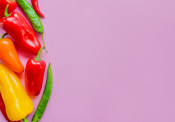Assorted colorful bell peppers and chili on a vibrant pink background with copyspace, ideal for...