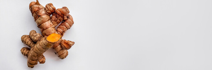 Fresh turmeric roots on a clean white background with copy space, perfect for health and wellness concepts