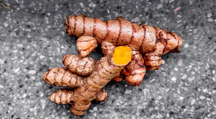 Fresh turmeric roots on a textured grey surface, highlighting the natural, organic concept with space for text, ideal for health and wellness themes