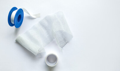 Medical bandage roll with blue dispenser and adhesive tape on a white background with copy space, suitable for healthcare and first aid-related themes