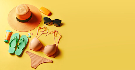 Un grand chapeau en osier, un bikini, une paire de lunettes de soleil, des tongs, des coquillages et de la crème solaire posés sur un fond jaune évoquant la plage, le sable, et les vacances d'été - obrazy, fototapety, plakaty