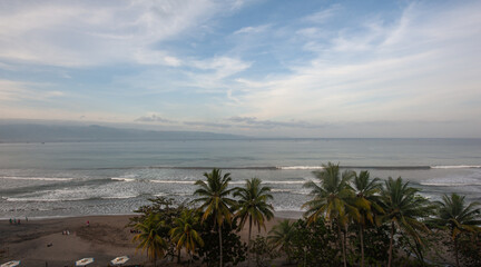 panoramic view of the beach at sunrise with palm trees and waves for surfing in Palabuhanratu, Sukabumi, west Java, Indonesia