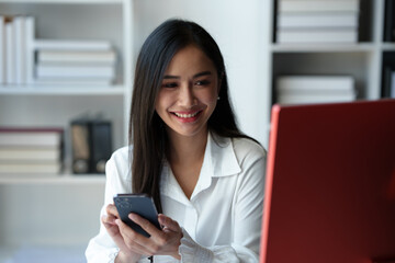 Obraz premium Accountant, Asian independent business woman Positive concept using smartphone to relax with mobile app and use chat business communication Contact online marketing that is extremely profitable.