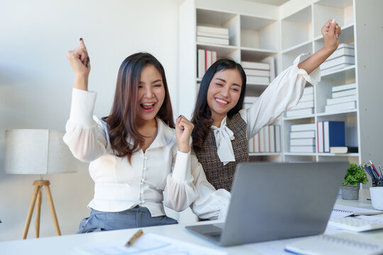 Two Asian businesswomen rejoicing over success in business, smiling and expressing joy. success in starting an online business partner teamwork concept.