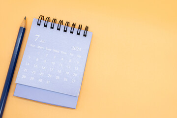 2024 July Calendar and pencil isolated on orange background. planning for business or travel...