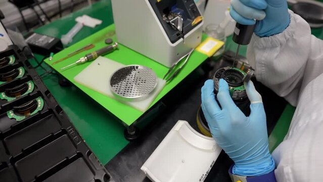 Close up shot of attach screws to the lens. Cinema lenses production. Manufacturing, industrial and technology concept.