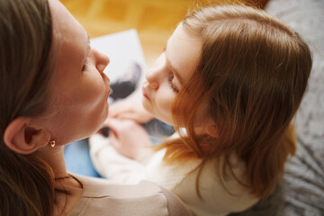 mother and daughter flips through a book with photos of dad and pregnant mom.