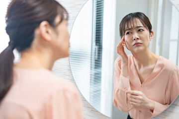 鏡を見て肌の調子を気にするミドルの日本人女性