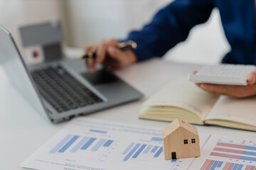 Man in a suit doing property tax calculations using a calculator of a house model