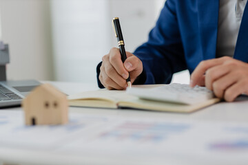 Man in a suit doing property tax calculations using a calculator of a house model