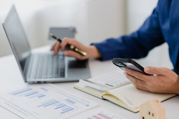 Man in a suit doing property tax calculations using a calculator of a house model
