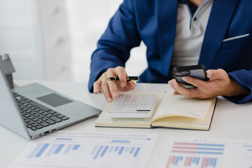 Man in a suit doing property tax calculations using a calculator of a house model