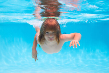 Young boy swim and dive underwater. Under water portrait in swim pool. Child boy diving into a swimming pool.