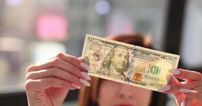 Woman checkups hundred dollar bill to detect counterfeit