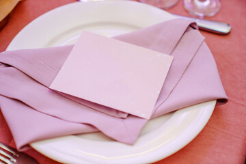 Table setting. A plate with purple napkins and a seating card. 