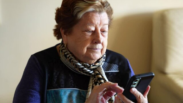 Modern and techy granny using a smartphone scrolling a lot, 4K