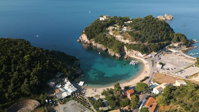 Aerial static high angle overview of secluded cove as ocean waves rippl on surface and cars drive to park in lot