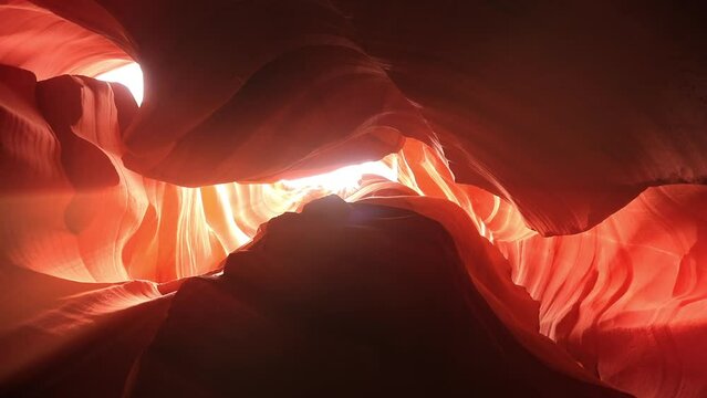 Low angle view of wavy sandstone walls in orange color of Antelope Canyon, Arizona, USA. Sun beams shining on red canyon walls. Curved sandstone ravines of Antelope Canyon. Travel concept, 4k footage