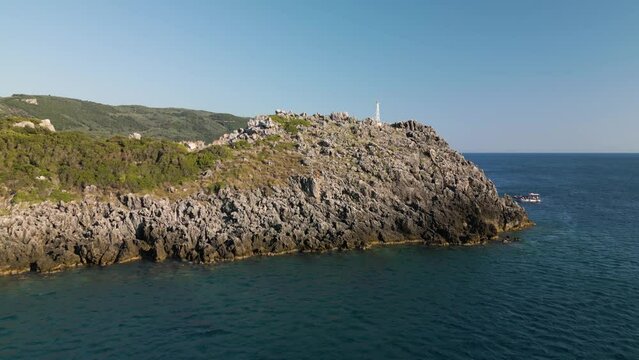 Drone dolly to jagged rocky outcropping rise to reveal stunning coastal getaway of Corfu Greece