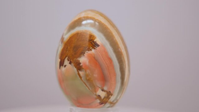 Onyx mineral egg slowly rotating on a turn table. White background.